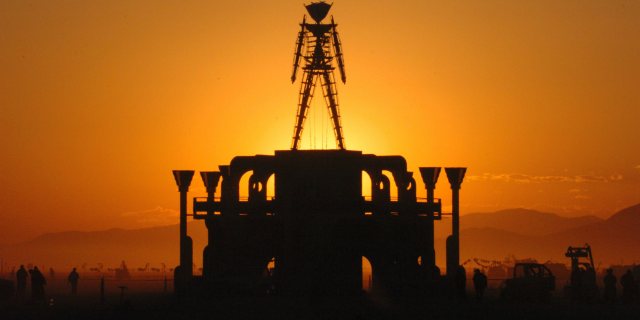 FILE - In this Sept. 2, 2006 file photo, The Man, a stick figured symbol of the Burning Man art festival, is silhouetted against a morning sunrise in Nevada's Black Rock Desert. Burning Man organizers say the U.S. government wants to place unreasonable conditions on a proposal to expand the counter-culture festival's capacity to 100,000, including more security searches and hardened barriers around the perimeter that the agency says would reduce vulnerability to terrorism. (AP Photo/Ron Lewis, File)